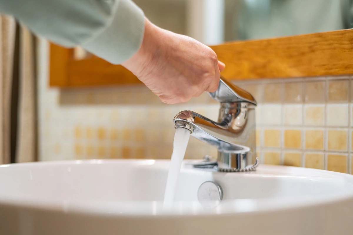 Une personne qui consomme de l'eau en ouvrant le robinet