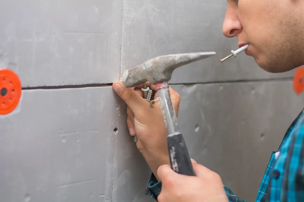 Une personne qui met une cheville dans du béton armé