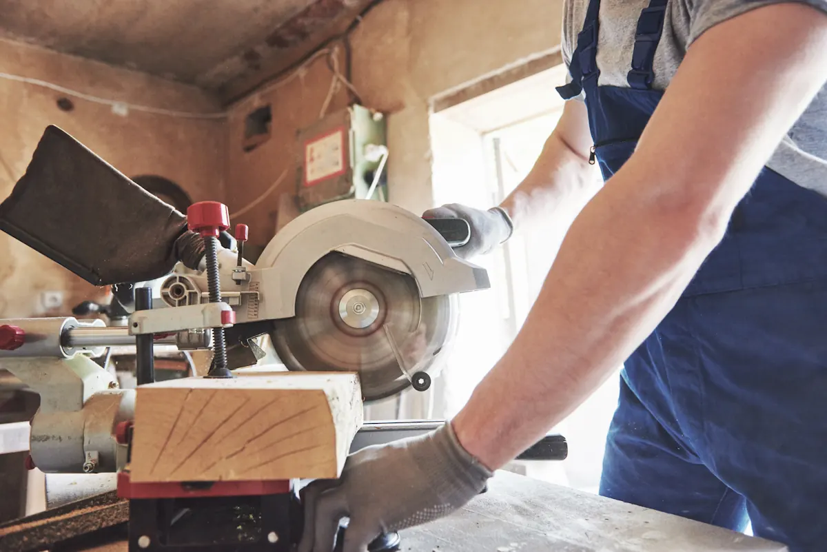 Un homme qui coupe du bois ave une scie circulaire
