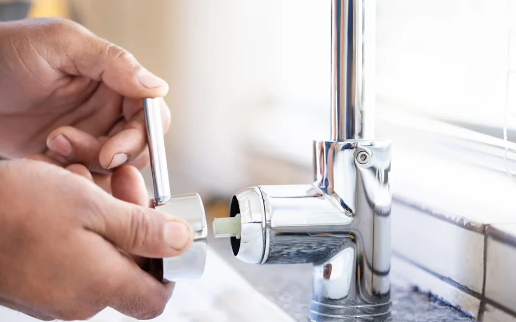 Une personne qui dégrippe un robinet d'arrivée d'eau