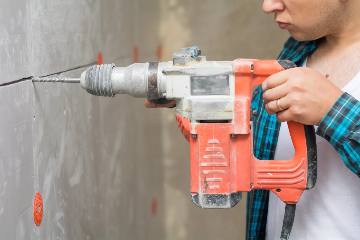 Une personne qui perce du béton très dure